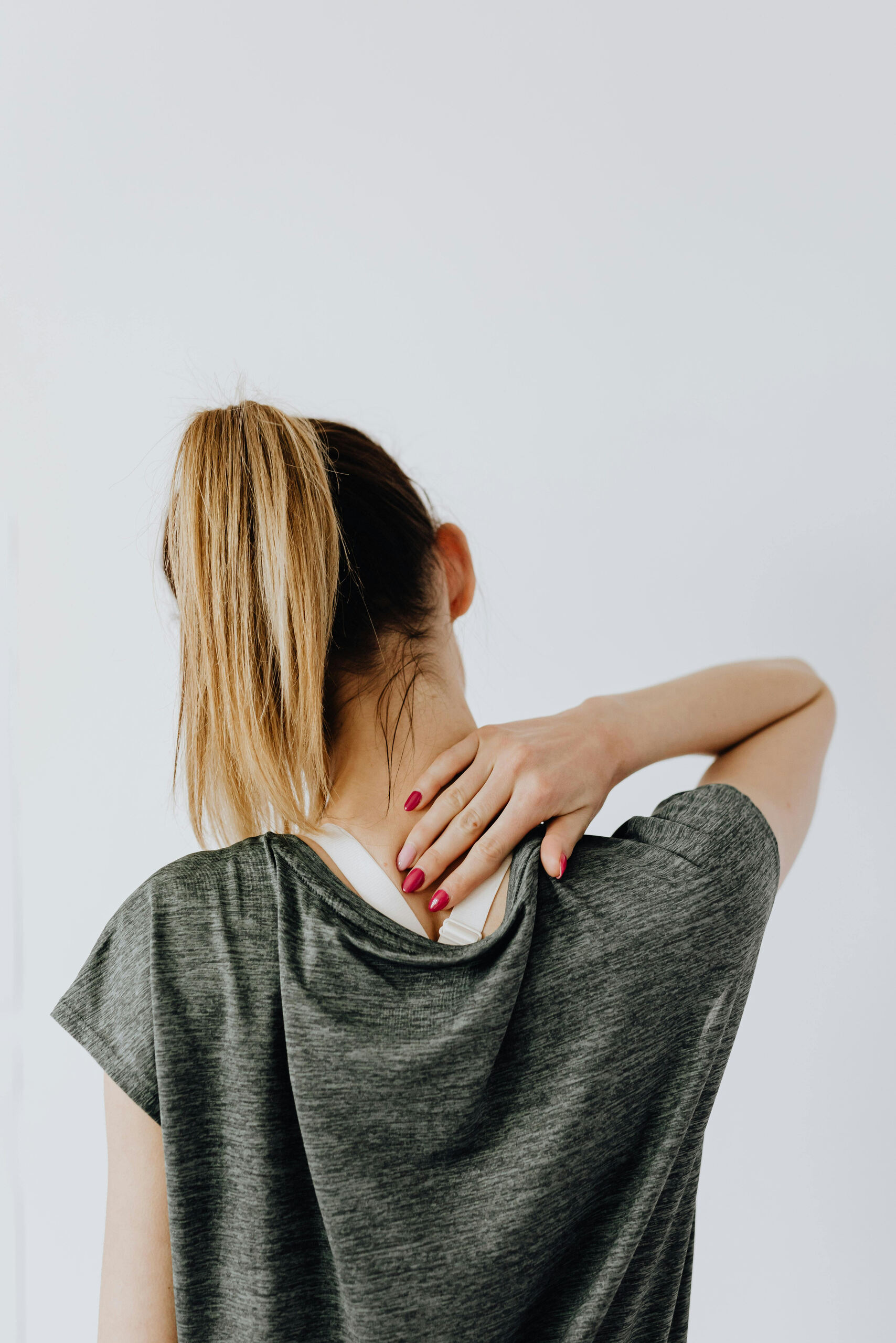 Woman reaching to rub a tight neck and shoulder